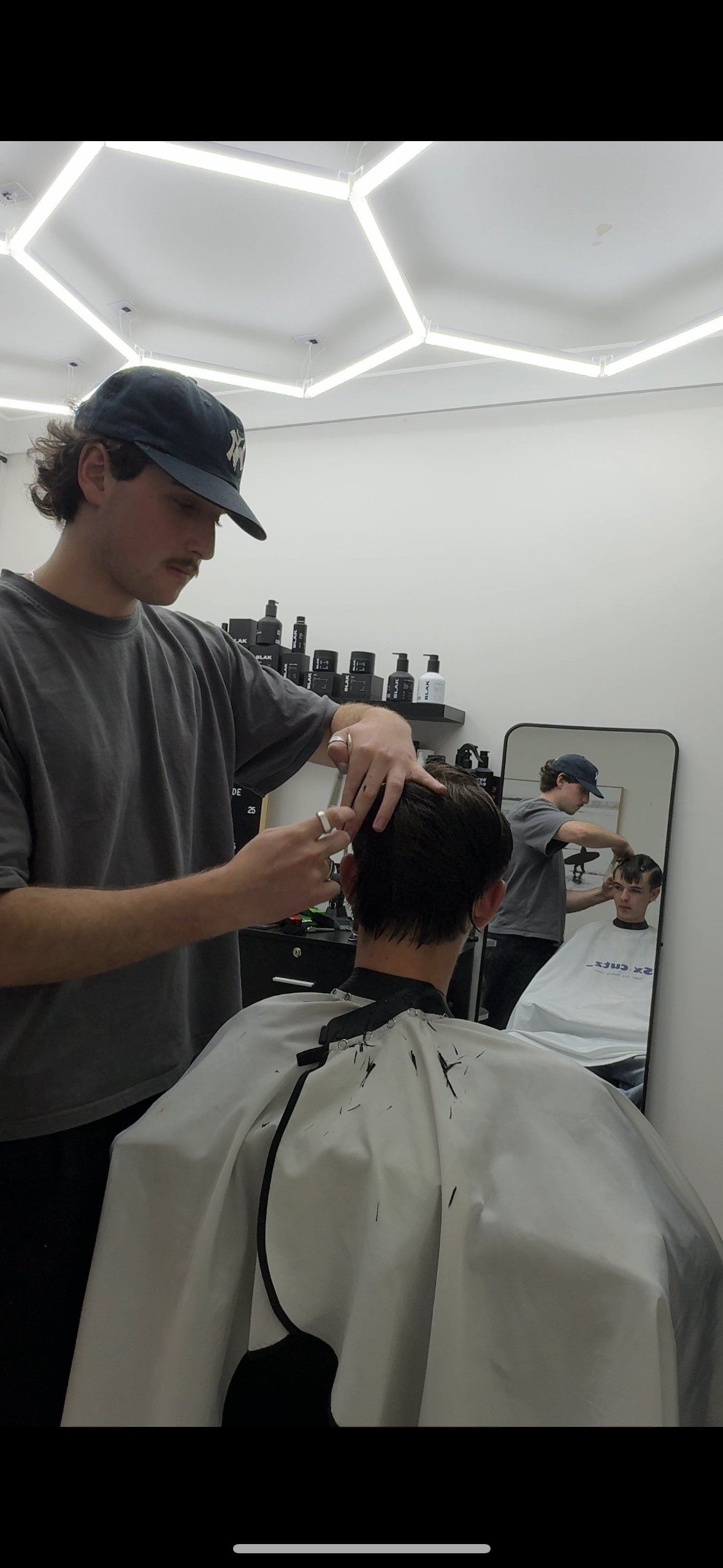 Saul cutting a client’s hair, reflected in the studio mirror